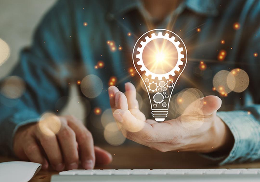 Light bulb sits in the palm of a person's hand.