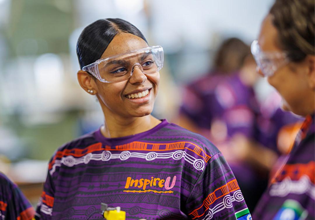 Student with branded InspireU shirt and safety goggles. 