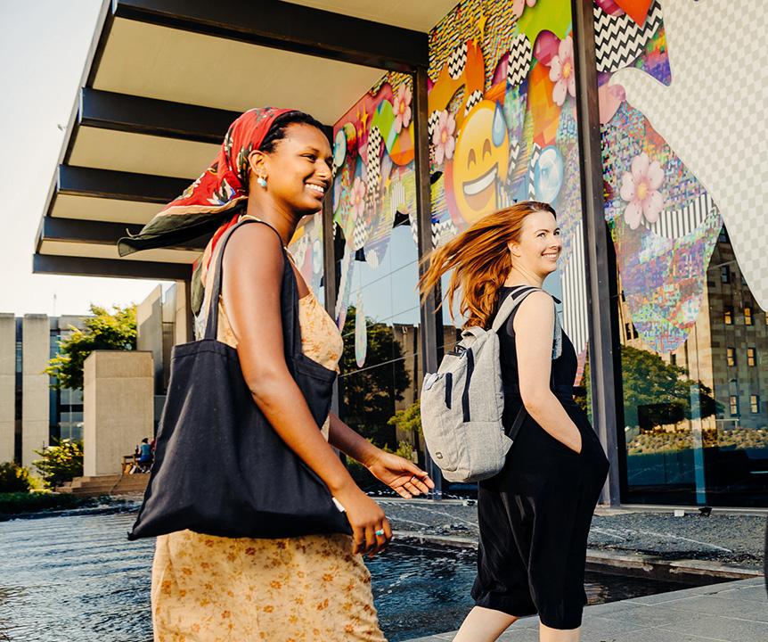 Two women walking into UQ Art Museum