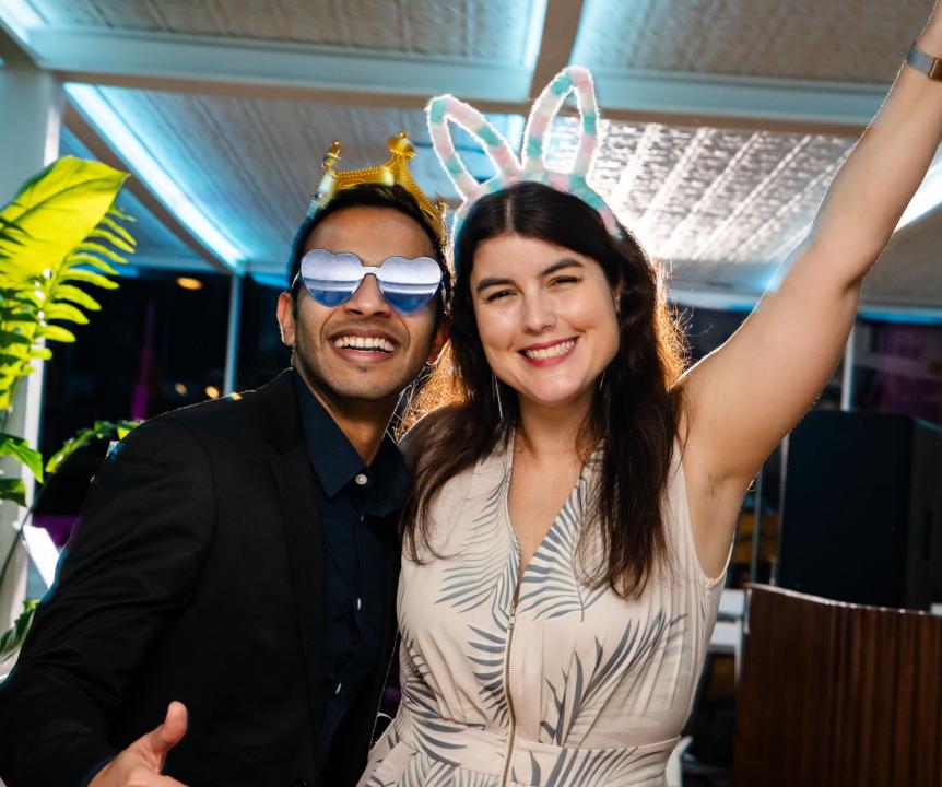 2 attendees wearing party prop crowns and sunglasses.