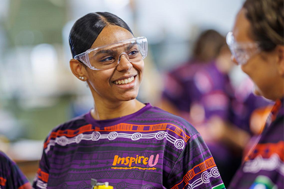 Student with branded InspireU shirt and safety goggles. 