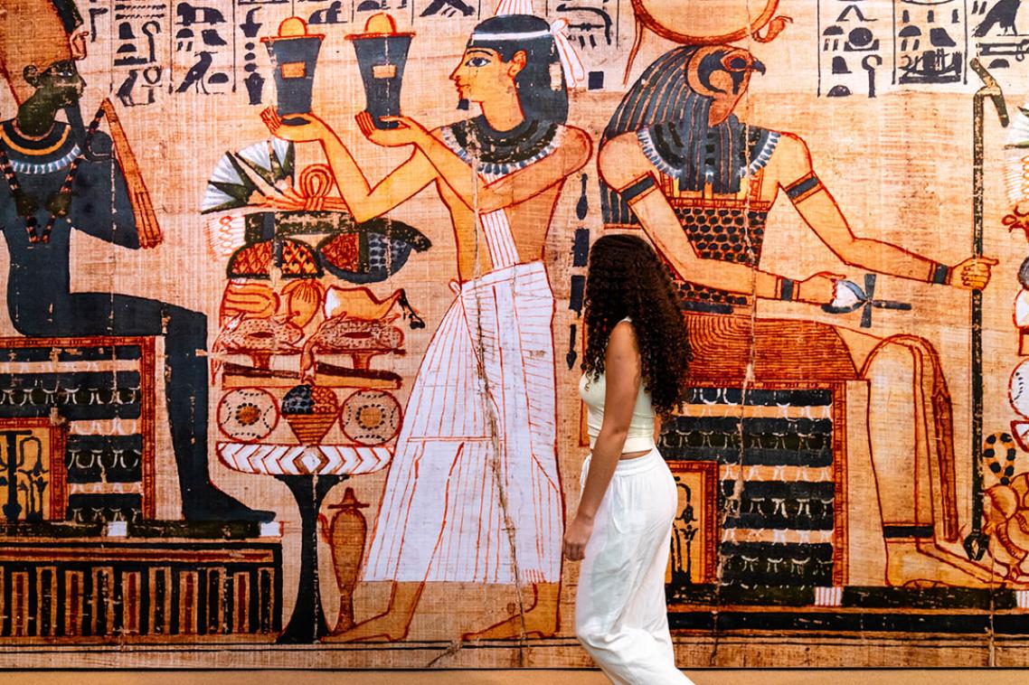 Women standing in front of a wall with ancient Egyptian paintings 